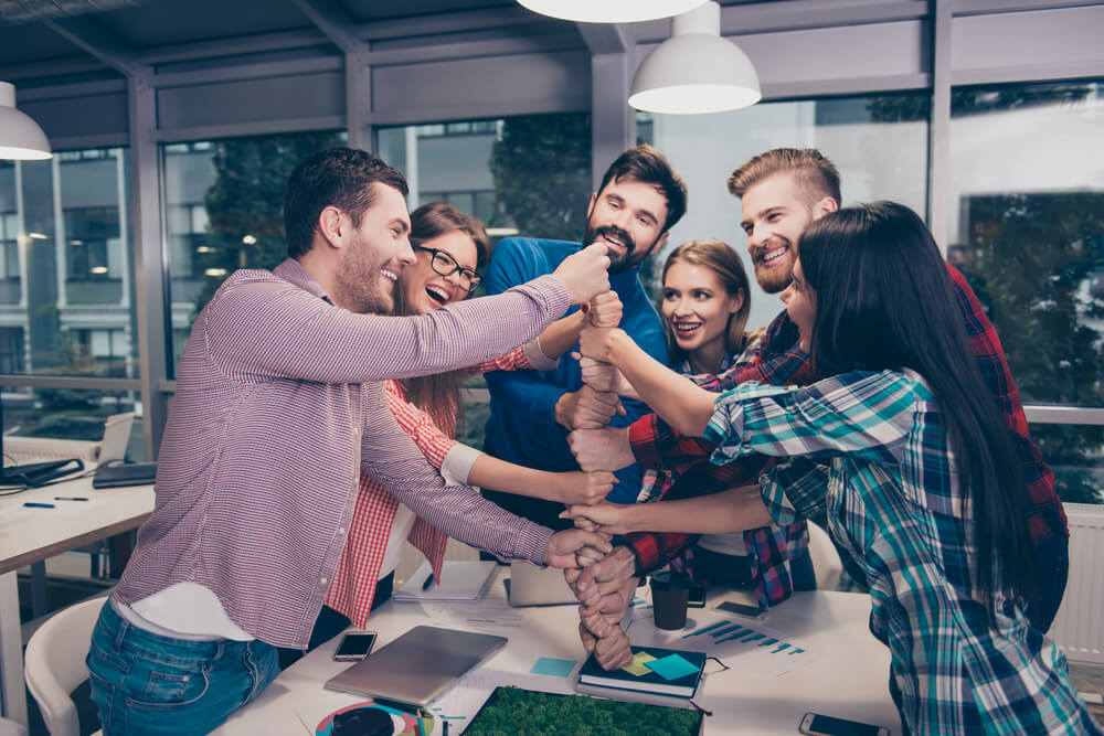 Happy Businesspeople Putting Their Fist On Top Of Each Other And Laughing. They Have Training