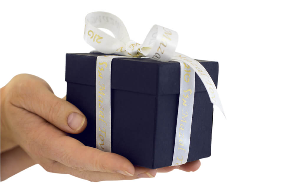 The woman's hands give a gift box with a Mazal Tov ribbon.