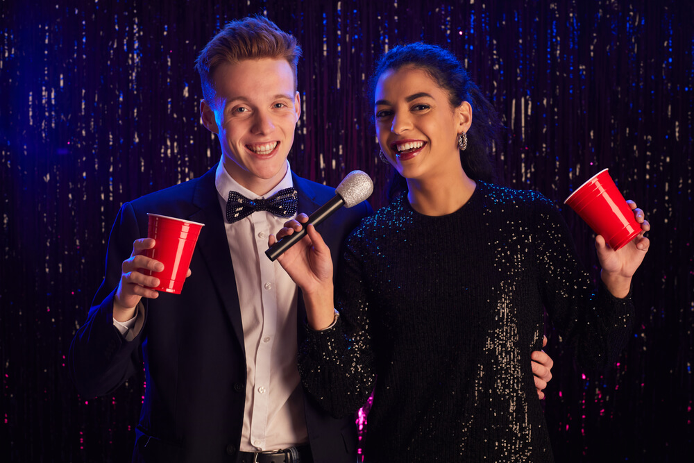 A young couple is holding a microphone while enjoying a karaoke party.