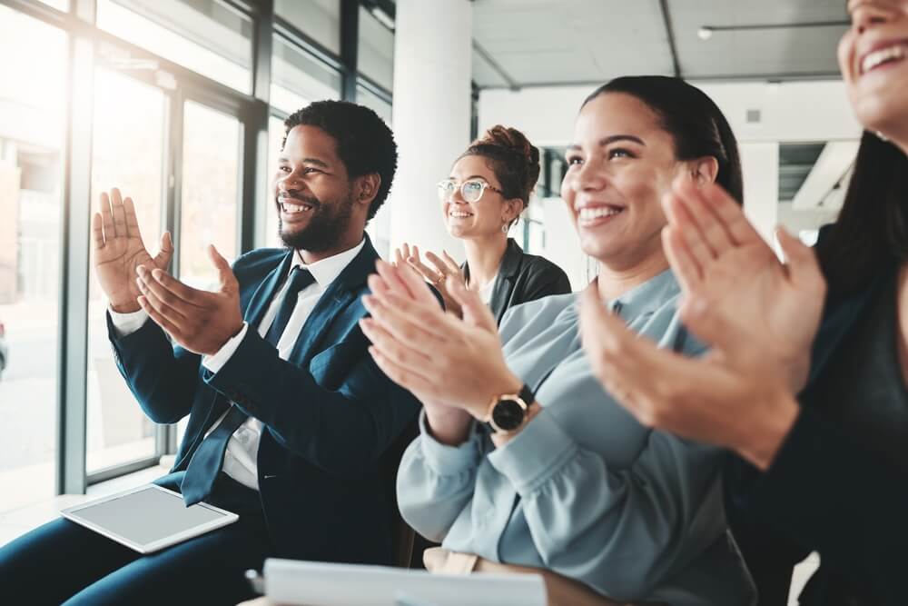Group of employees clapping for presentation, goals, or company targets.