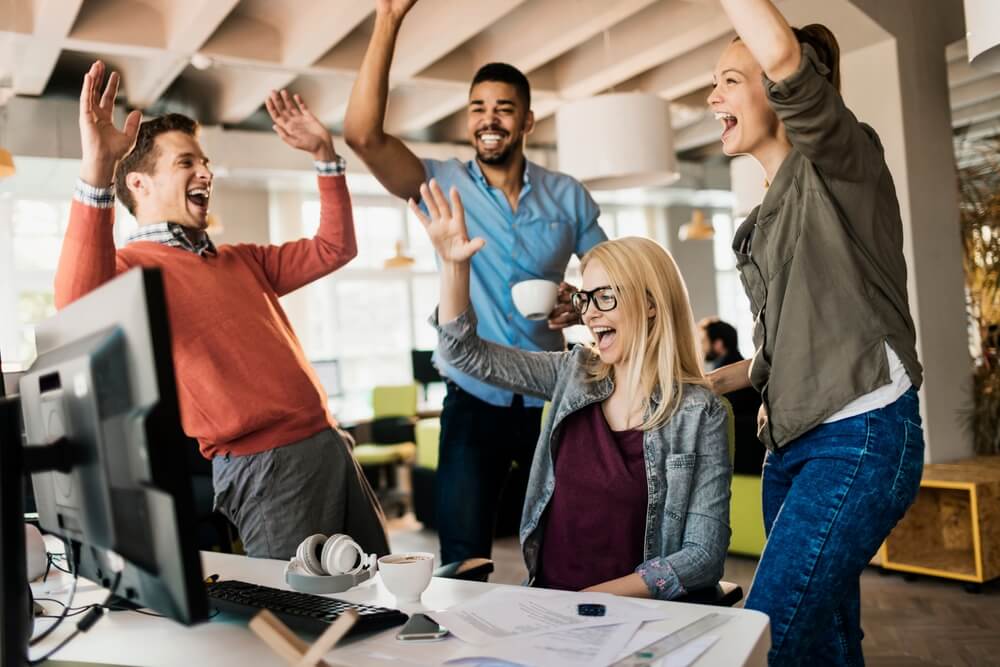 A group of diverse co-workers celebrating in the office.