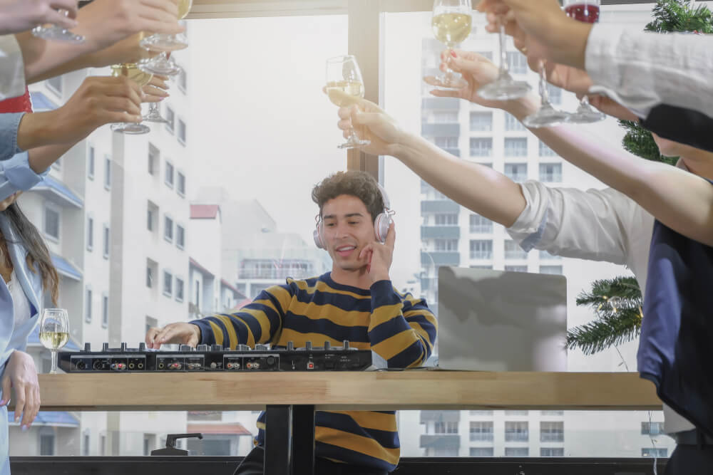 A DJ man mixing turntable in corporate party with group of business people.