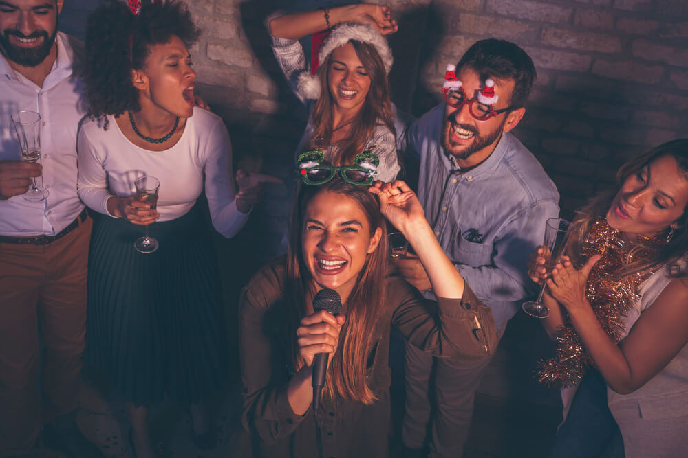 Group of young people having fun at Christmas party, singing karaoke and dancing.