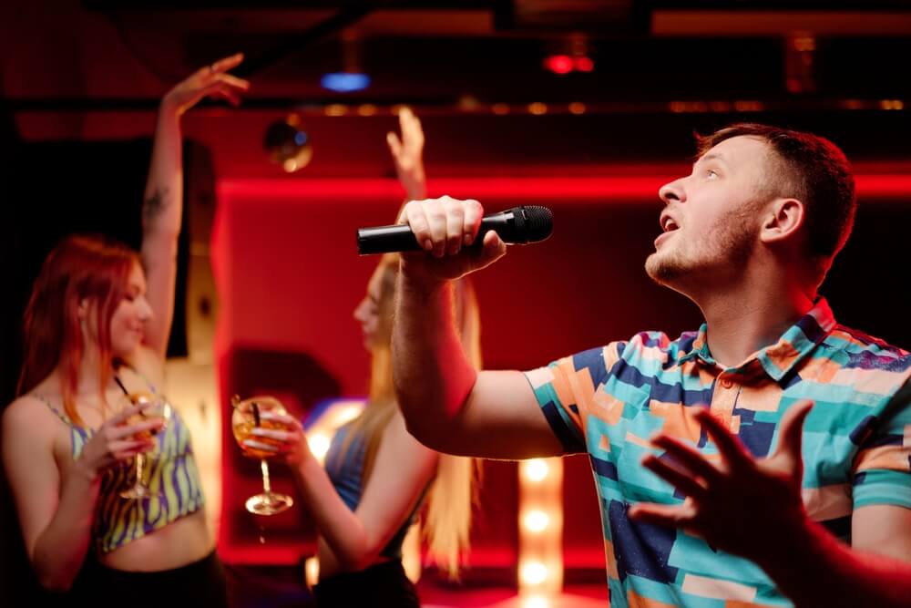 Happy young man singing karaoke.